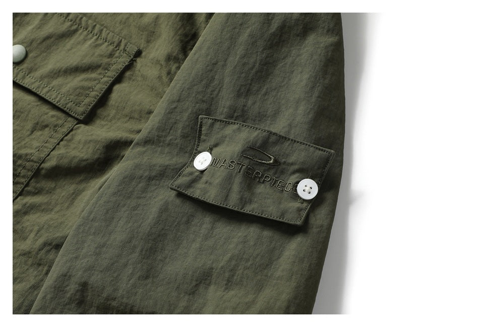 Olive-green sleeve pocket with white buttons and embroidered lettering.