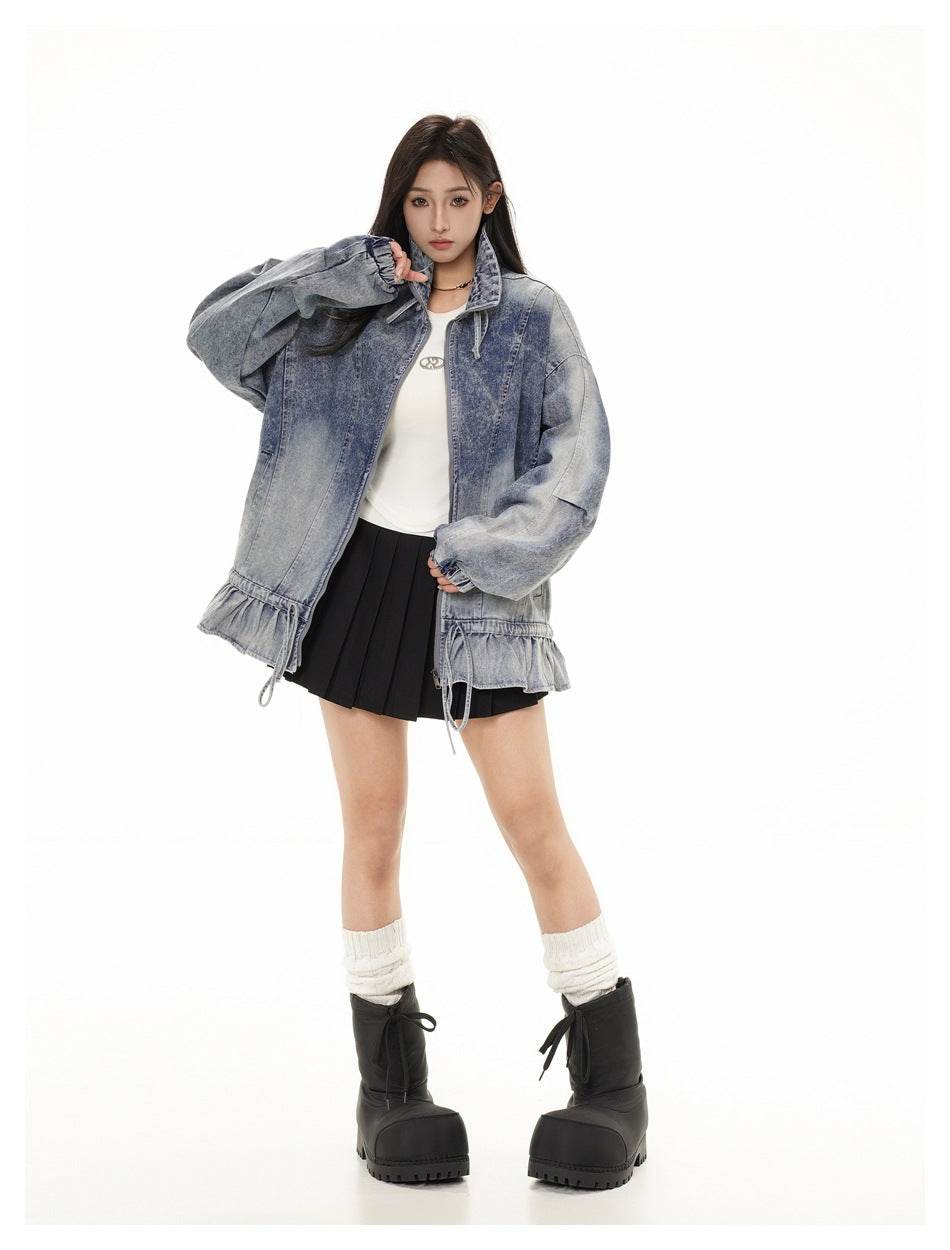 Full-length front view of a model wearing an oversized washed blue denim jacket with a ruffled drawstring hem.