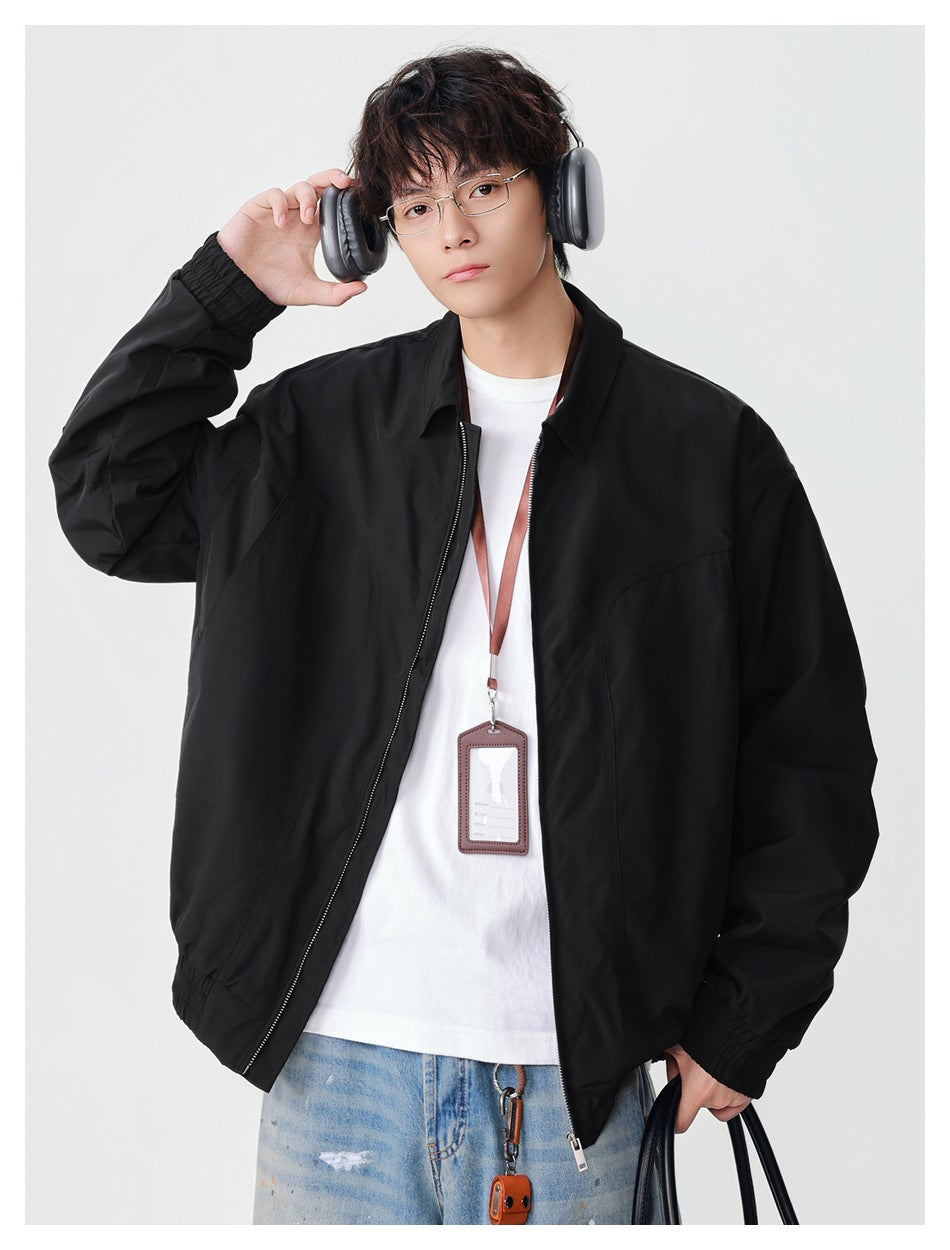 Model wearing a black collared zip jacket with elastic cuffs and hem, adjusting over-ear headphones.