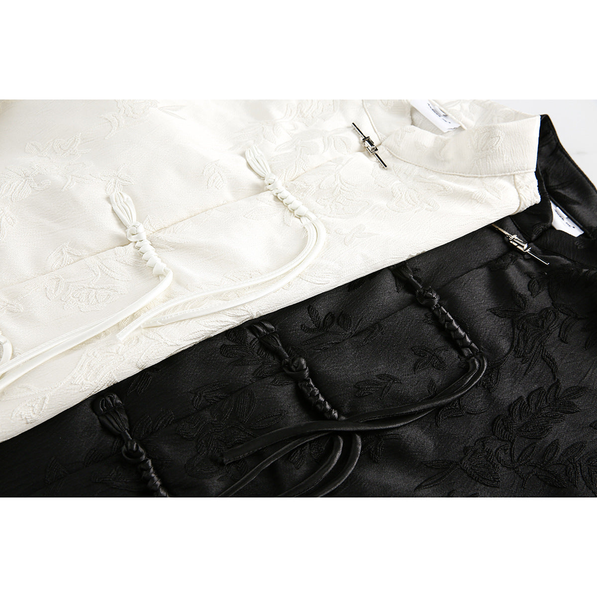 Close-up of ivory and black floral-patterned shirts showing braided frog closures and cords.