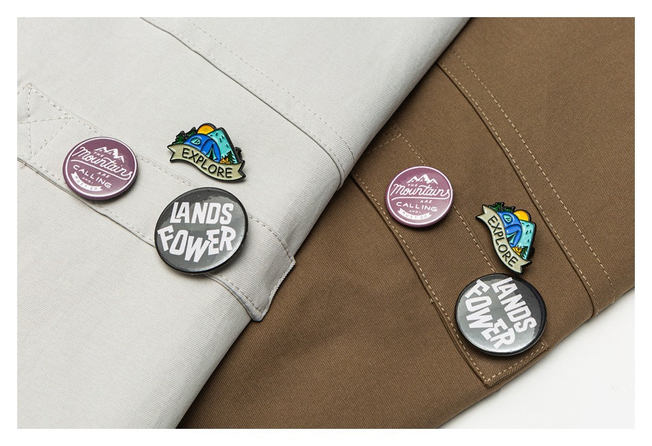 Close-up of beige and brown jacket pockets with colorful English-text pins attached.