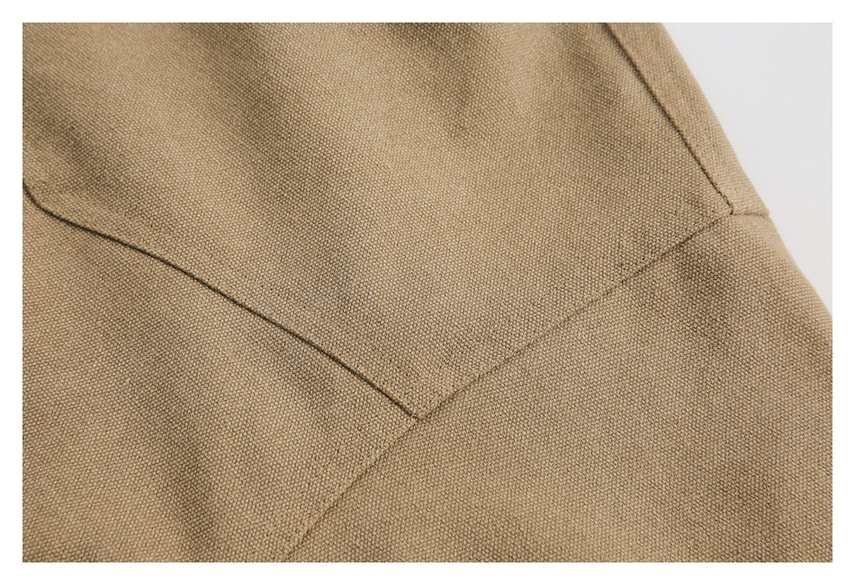 Close-up of stitching and angled seam details on tan textured jacket fabric.