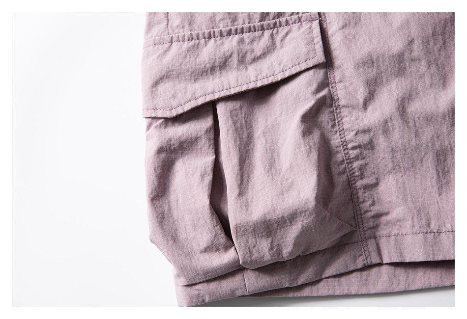 Close-up of a dusty mauve cargo short pocket with a flap and stitched seams.