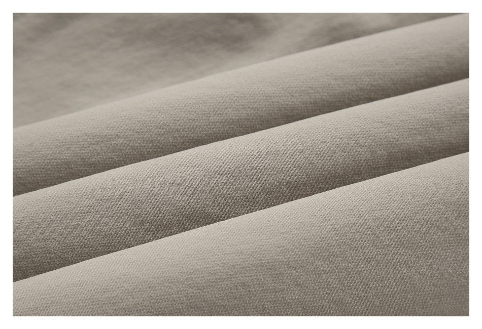 Close-up of light taupe fabric arranged in soft folds, showing its surface texture.