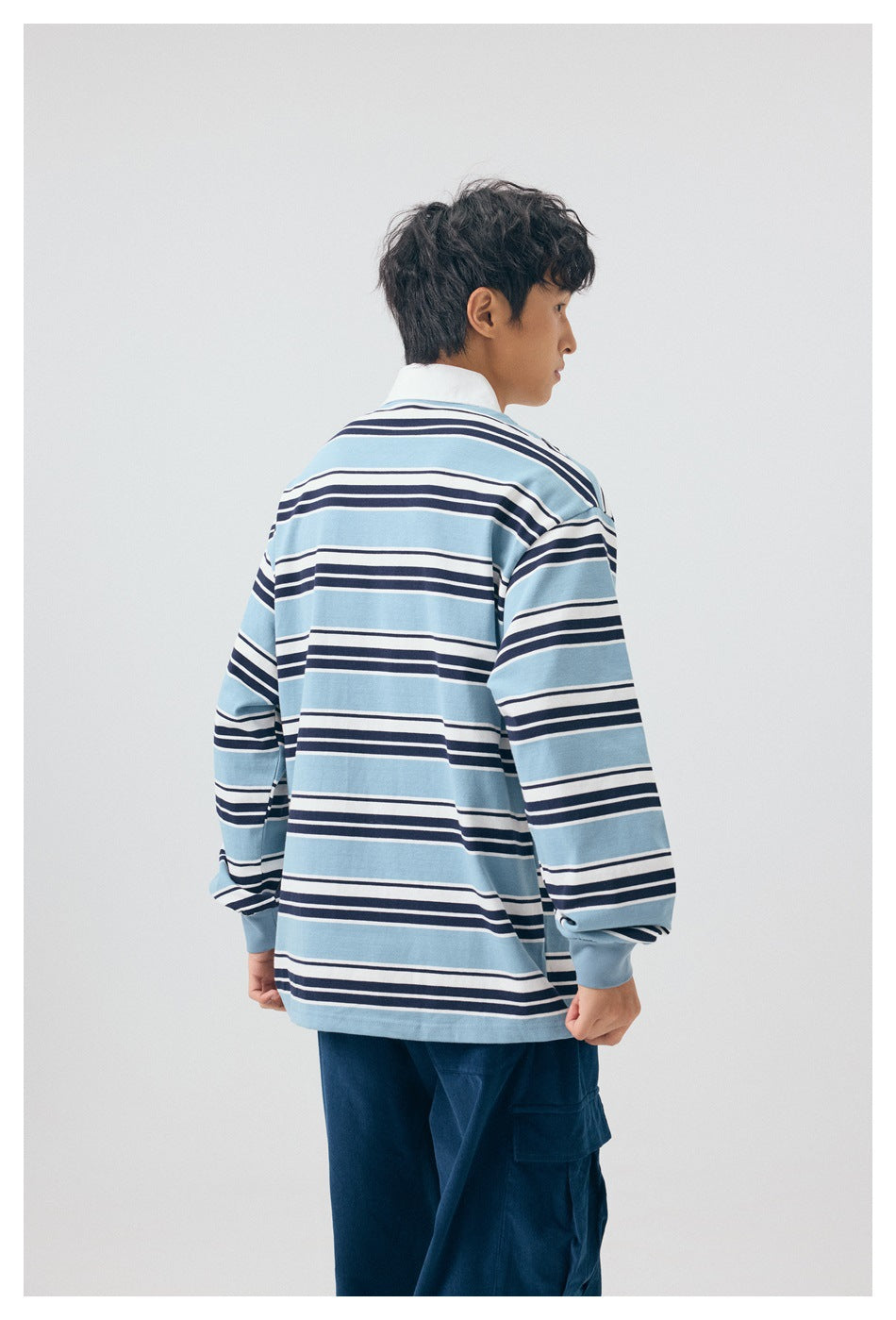 Back view of a model wearing a blue, white, and navy striped long-sleeve collared shirt.