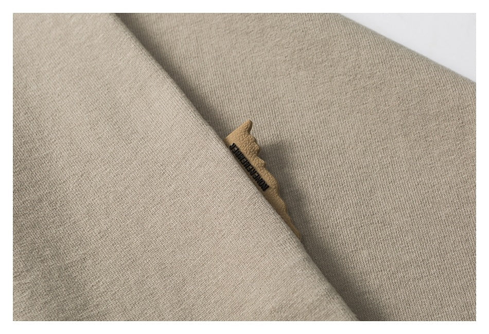 Close-up of beige garment fabric folds with a small tan leather tab bearing dark lettering.