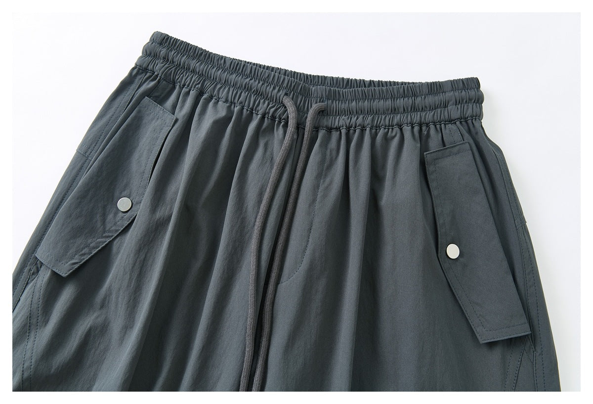 Close-up of the front waistband and snap-button flap pockets on dark charcoal cargo pants.
