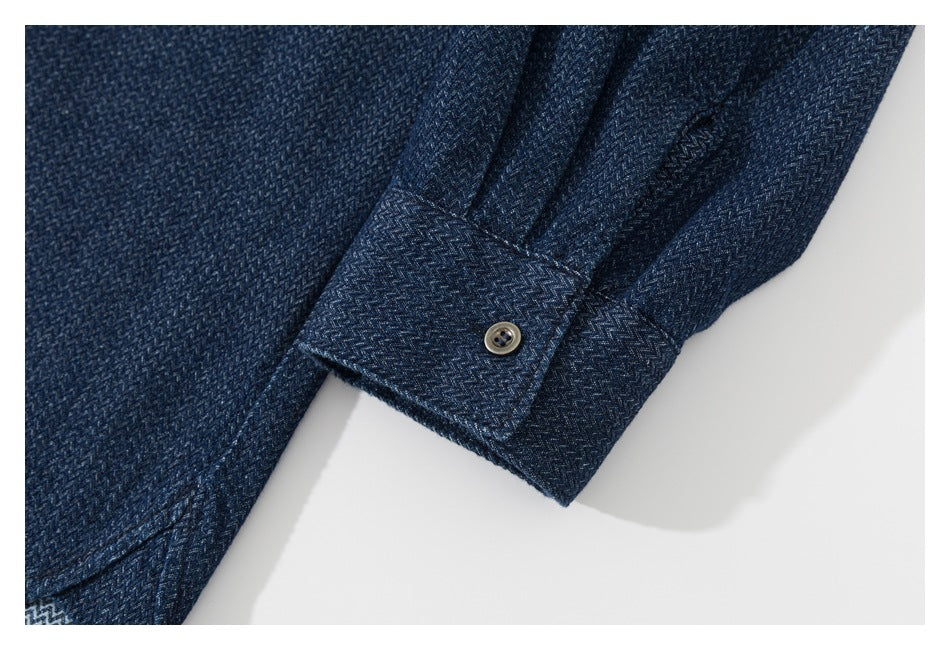 Close-up of a dark navy patterned shirt sleeve and buttoned cuff on a white background.