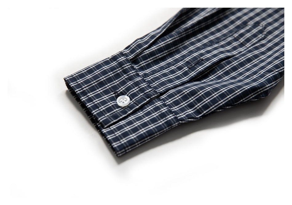 Close-up of a navy plaid shirt cuff with a white button on a white background.