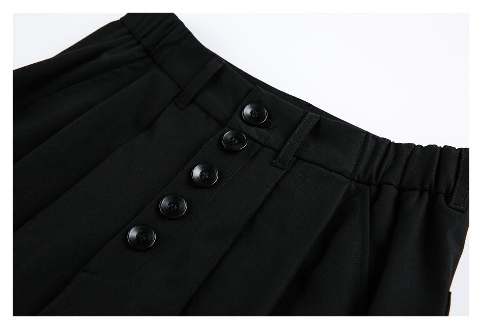 Close-up of the black shorts' pleated waistband, belt loops and five-button front closure.