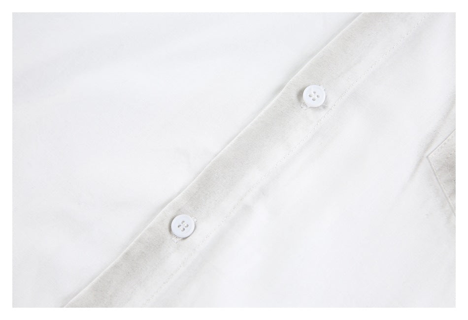 Close-up of two white buttons and stitching along a white shirt placket.