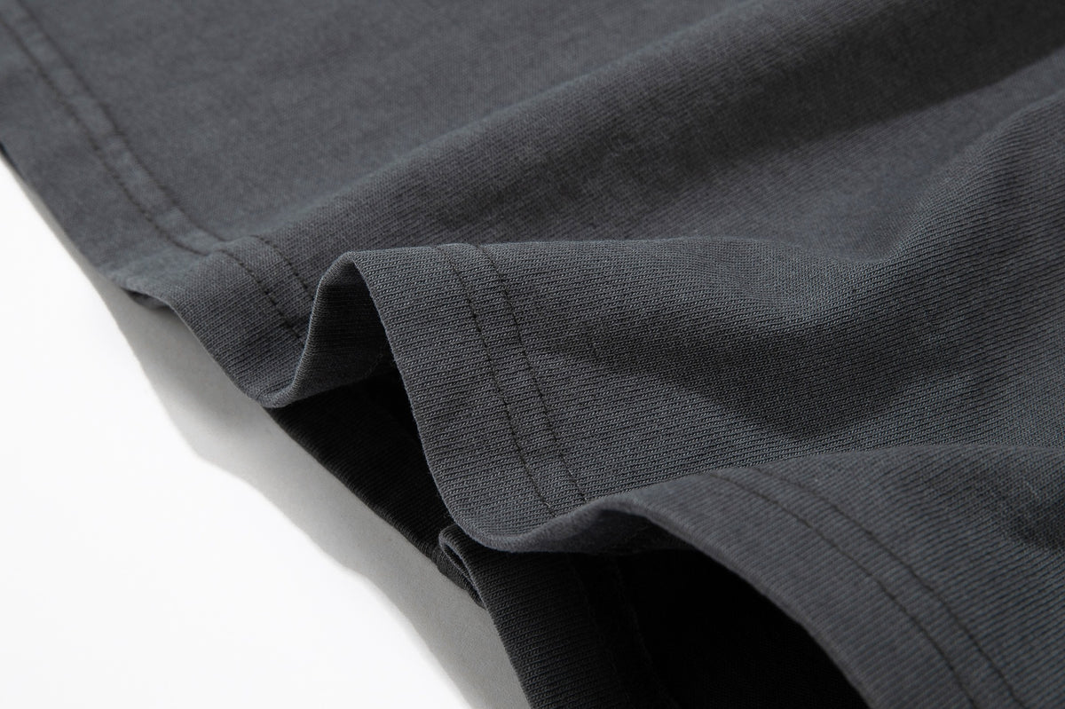 Close-up of a charcoal gray garment hem with a folded edge and visible stitching.