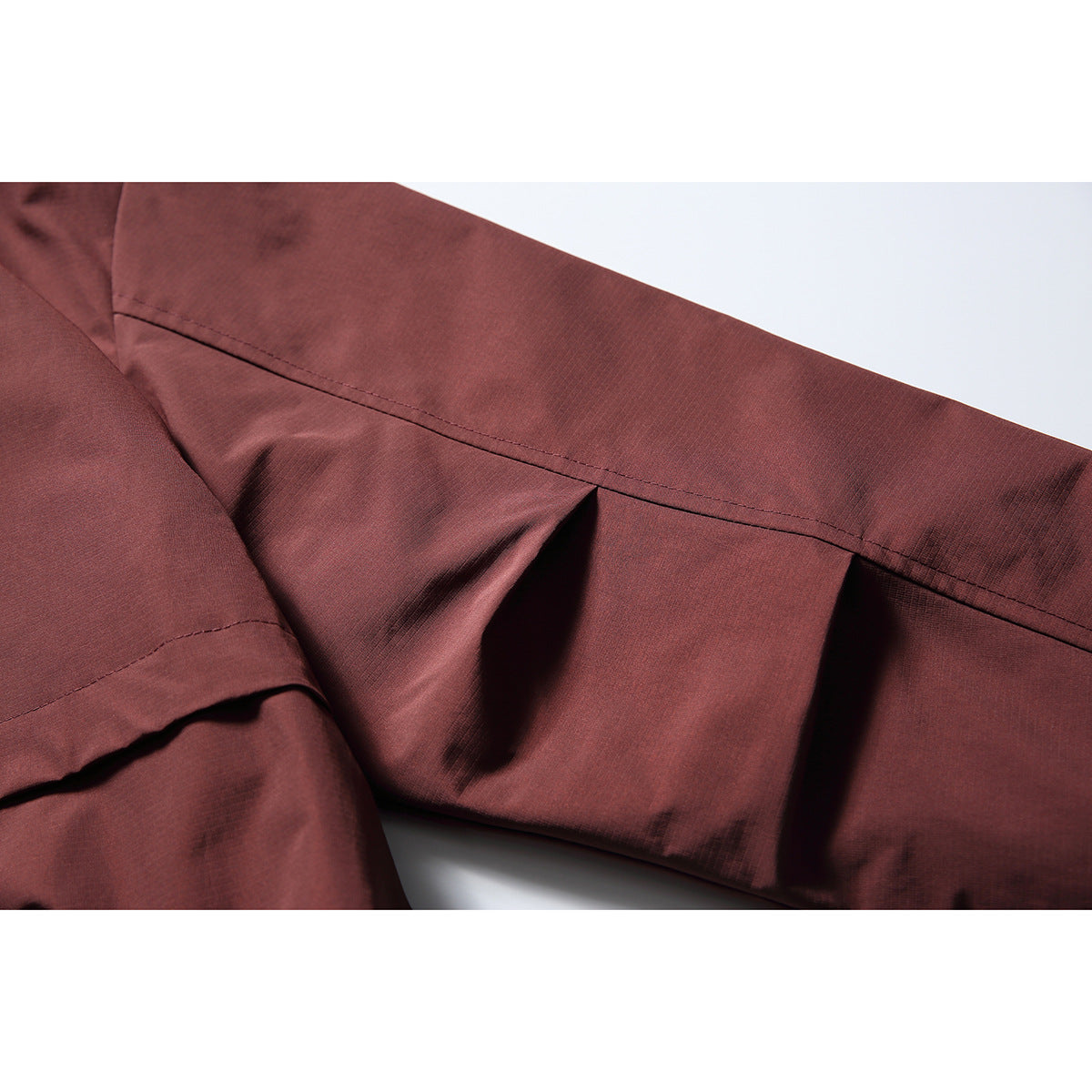 Close-up of the burgundy jacket’s sleeve and stitched panel seams.