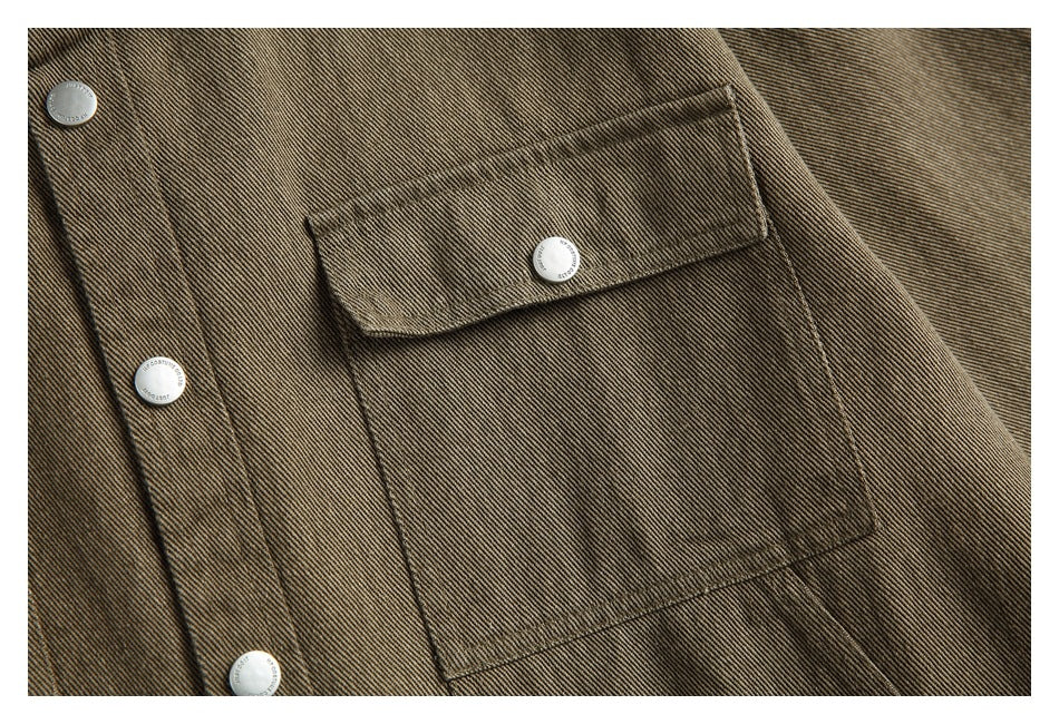 Close-up of a flap chest pocket and silver snap buttons on the brown-olive jacket.