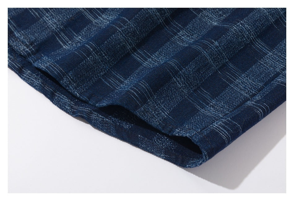 Close-up of the hem edge of a dark blue plaid garment on a white background.