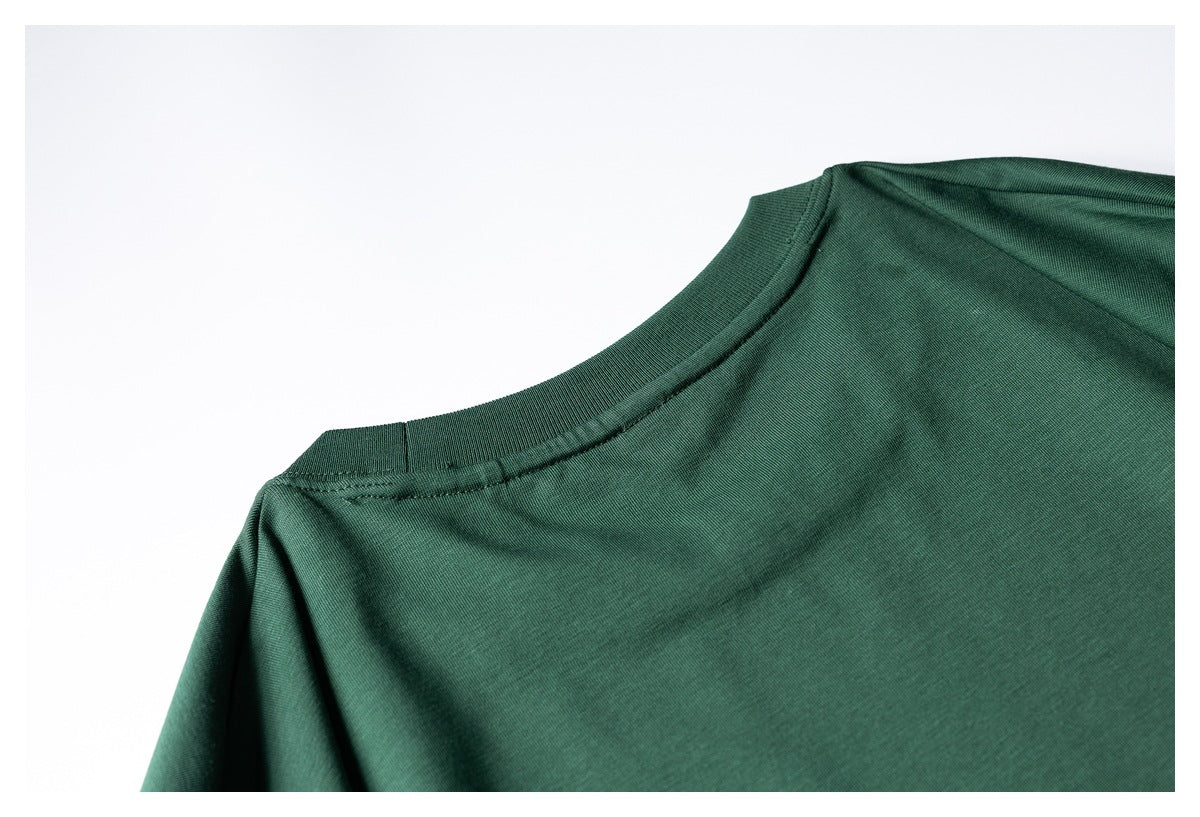 Close-up of a dark green shirt’s ribbed crew neckline and shoulder stitching.