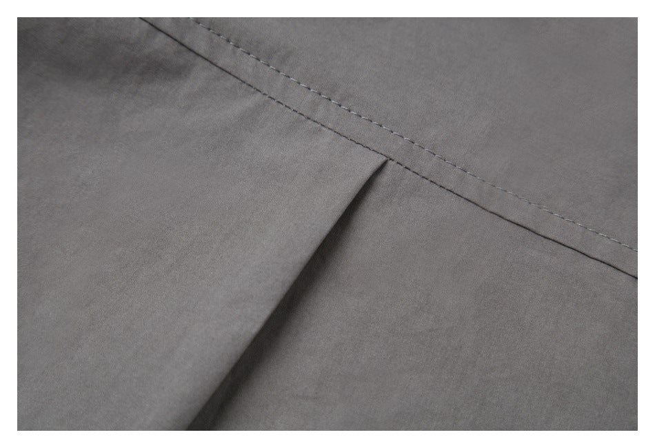 Close-up of gray garment fabric showing a stitched seam and folded pleat.
