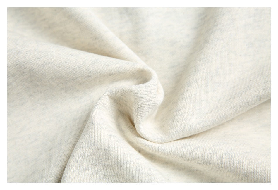 Close-up of light heathered sweatshirt fabric softly draped to show its surface and texture.