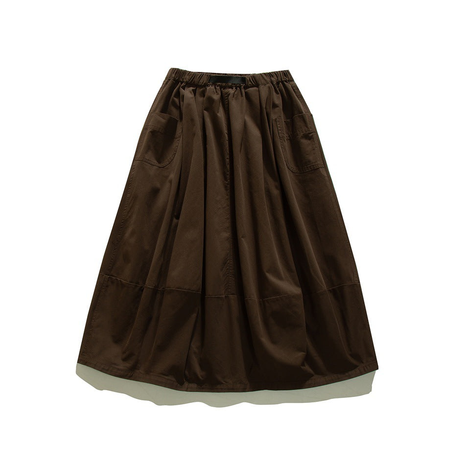 Brown flared skirt laid flat, with an elastic waistband, two front patch pockets, and a horizontal lower panel seam.