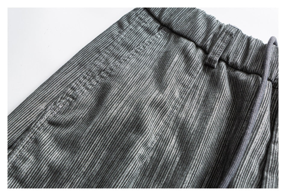 Close-up of gray striped pants fabric and waistband with a small stitched detail.