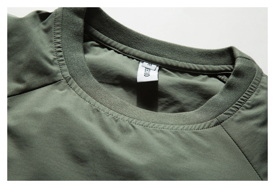 Close-up of a muted-green shirt's ribbed crew neckline and sewn-in neck tag.