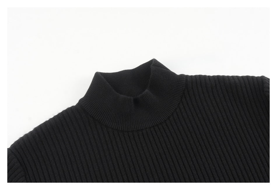 Close-up of a black ribbed knit sweater showing its high crew neckline and shoulder.