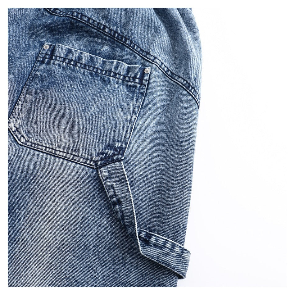 Close-up of a blue denim pocket with metal rivets, contrast stitching, and a turned-up hem.