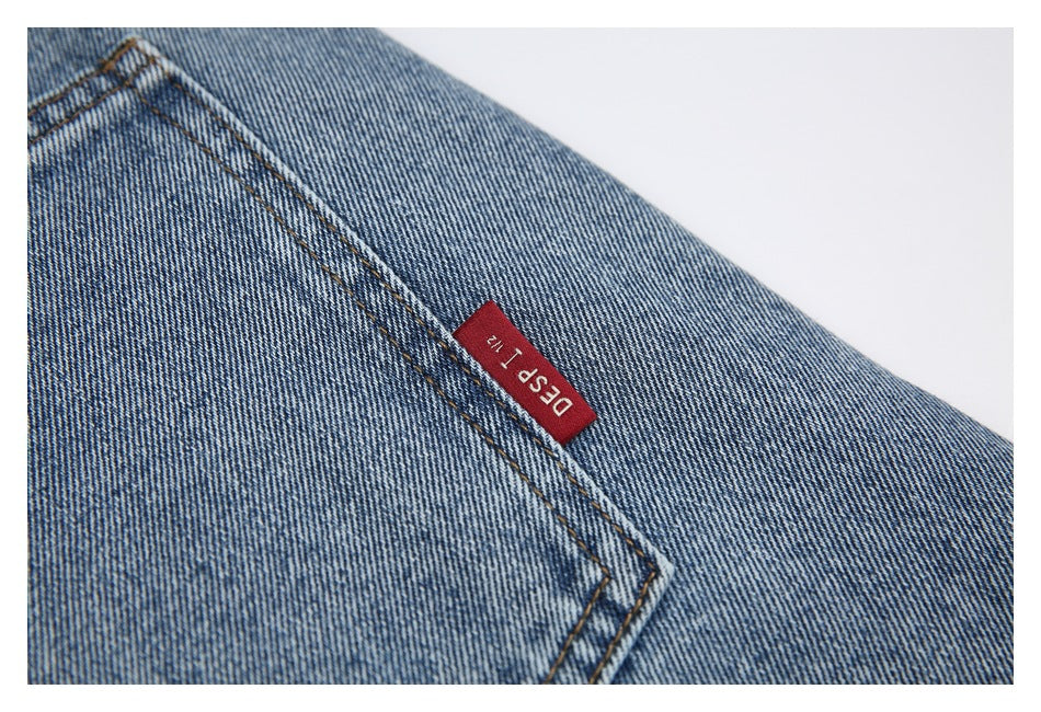 Close-up of faded blue denim and pocket stitching with a small red fabric tag.