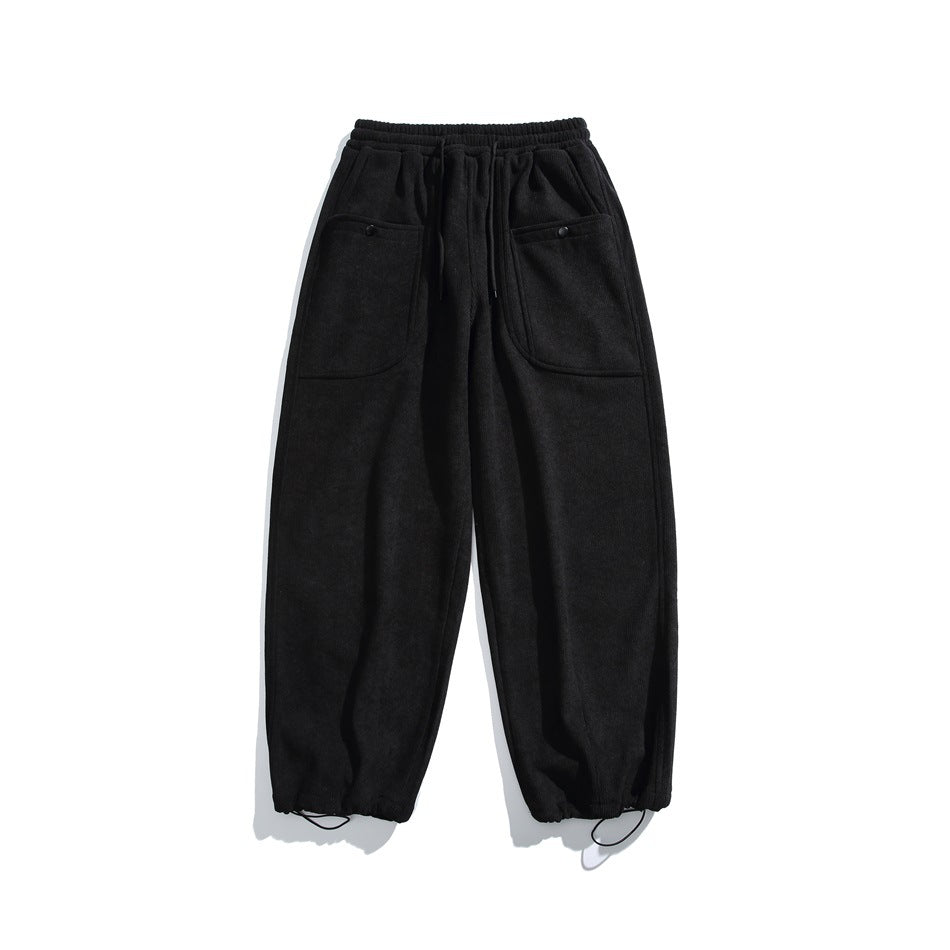Black relaxed pants flat lay with drawstring waist, large snap-button front pockets and drawstring hems