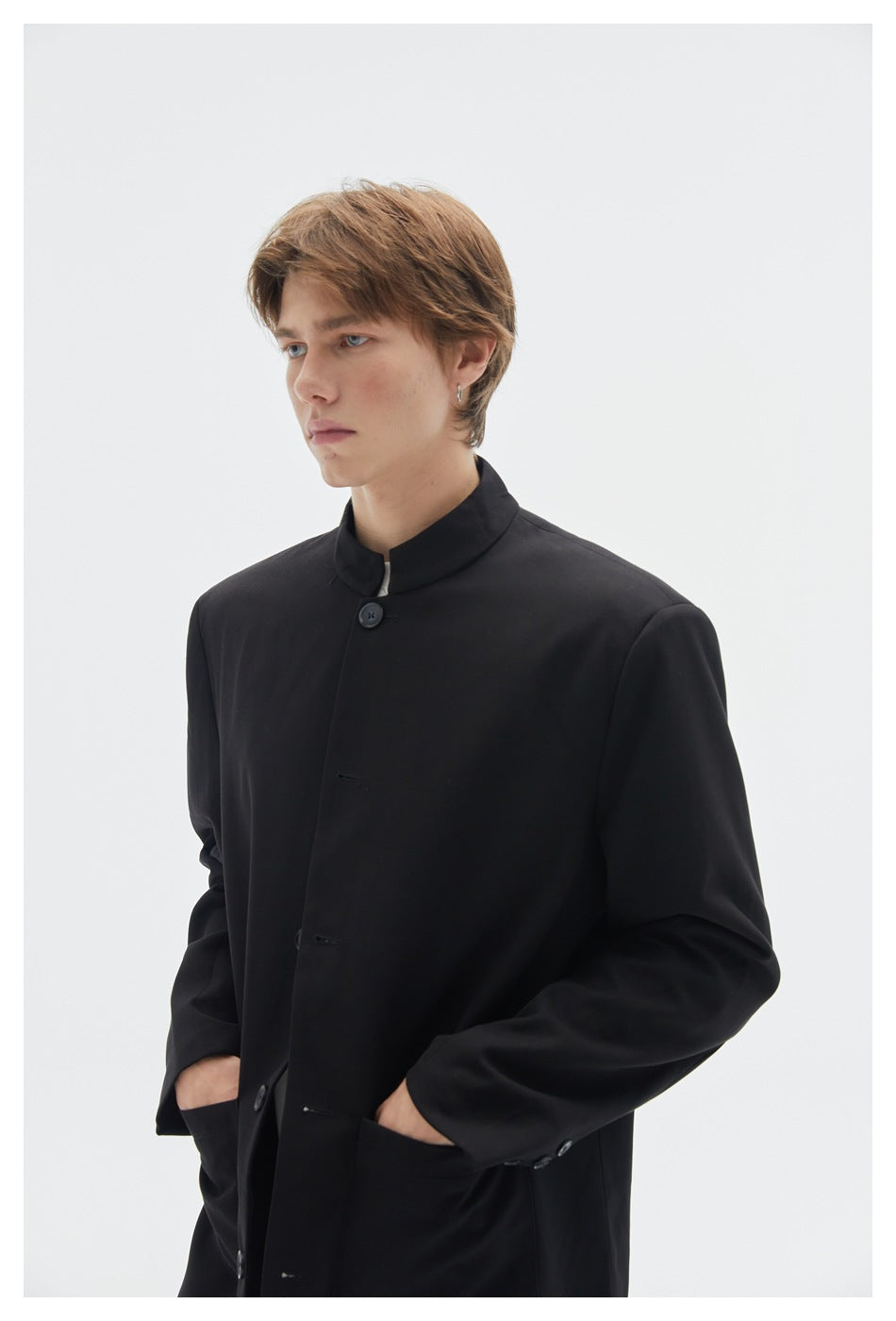 Close view of a model wearing a black stand-collar jacket, showing its button front, sleeve buttons and front pockets.
