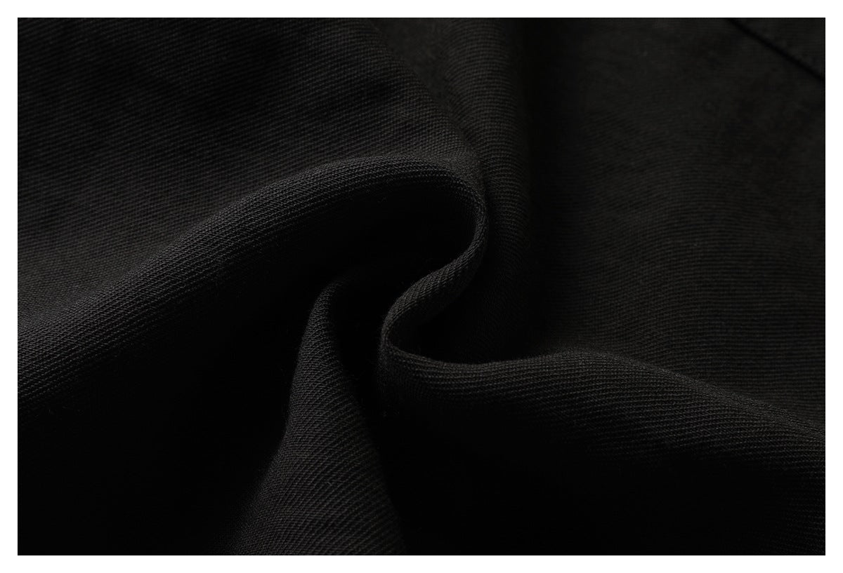 Close-up of black fabric folded into soft ridges, showing its visible weave.
