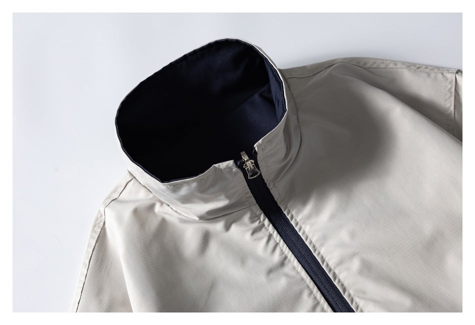 Close-up of an ivory jacket with a dark navy-lined stand collar and front zipper.