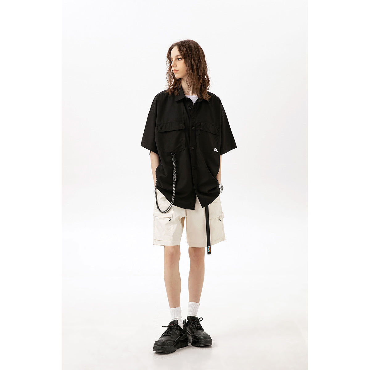 Model wearing a black oversized short-sleeve shirt and ivory cargo shorts with utility pockets.