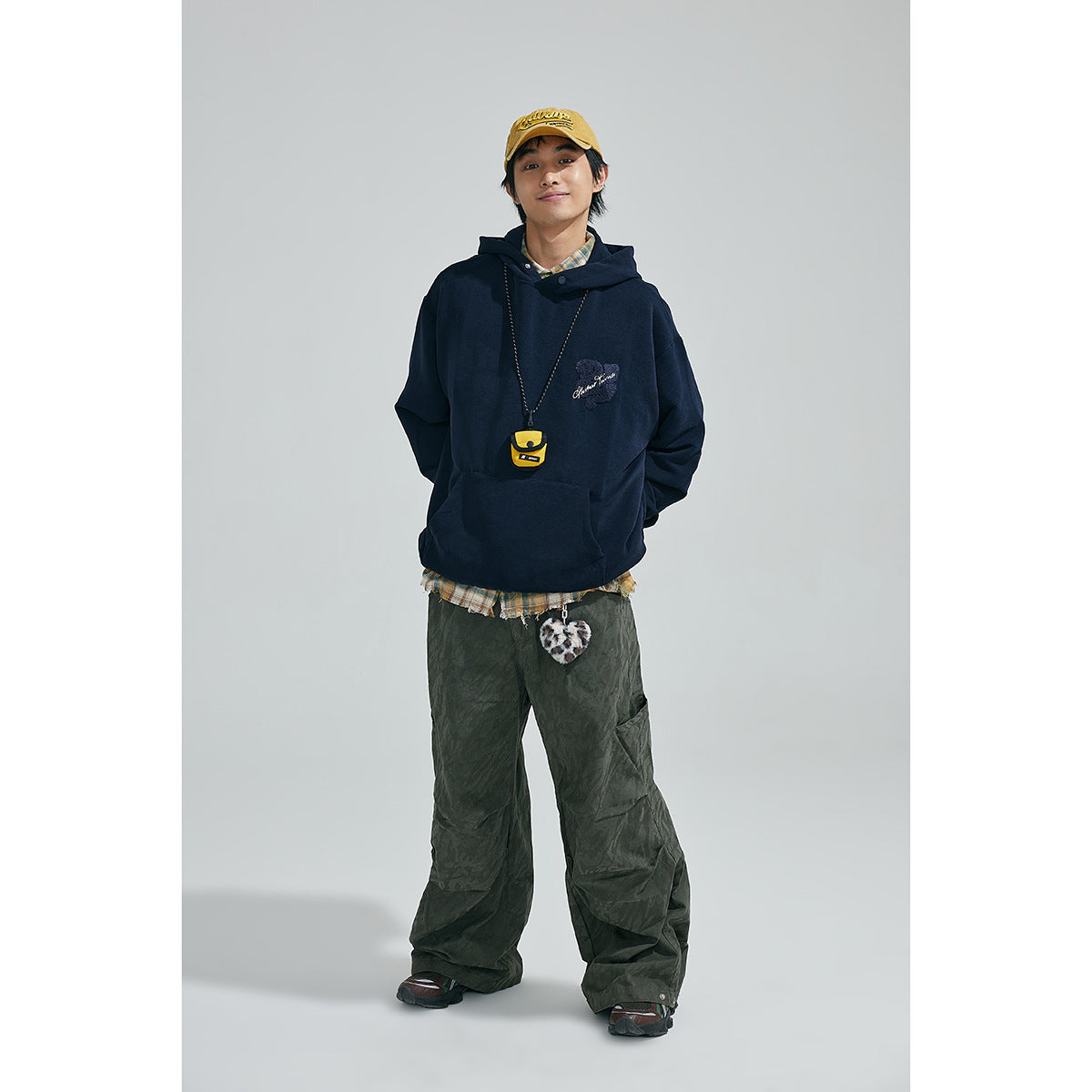 Full-length front view of a model wearing a navy hoodie with an embroidered chest design.