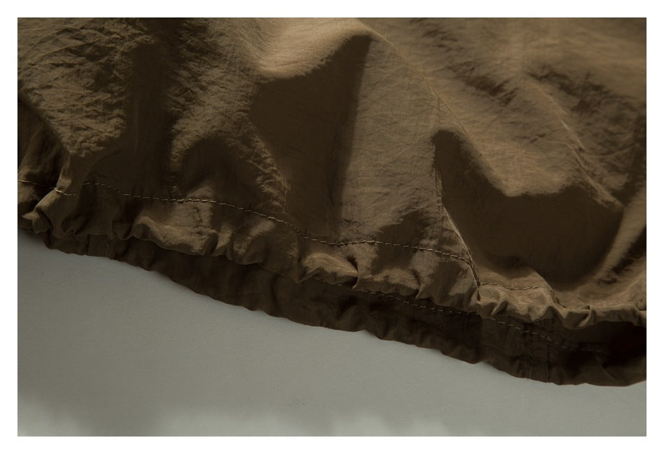 Close-up of a brown garment’s gathered, stitched hem.
