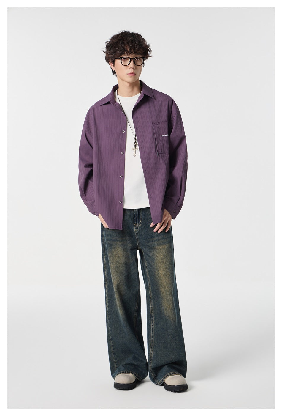 Full-length model wearing a muted purple button-front shirt with a chest pocket, white tee, and wide-leg faded jeans.