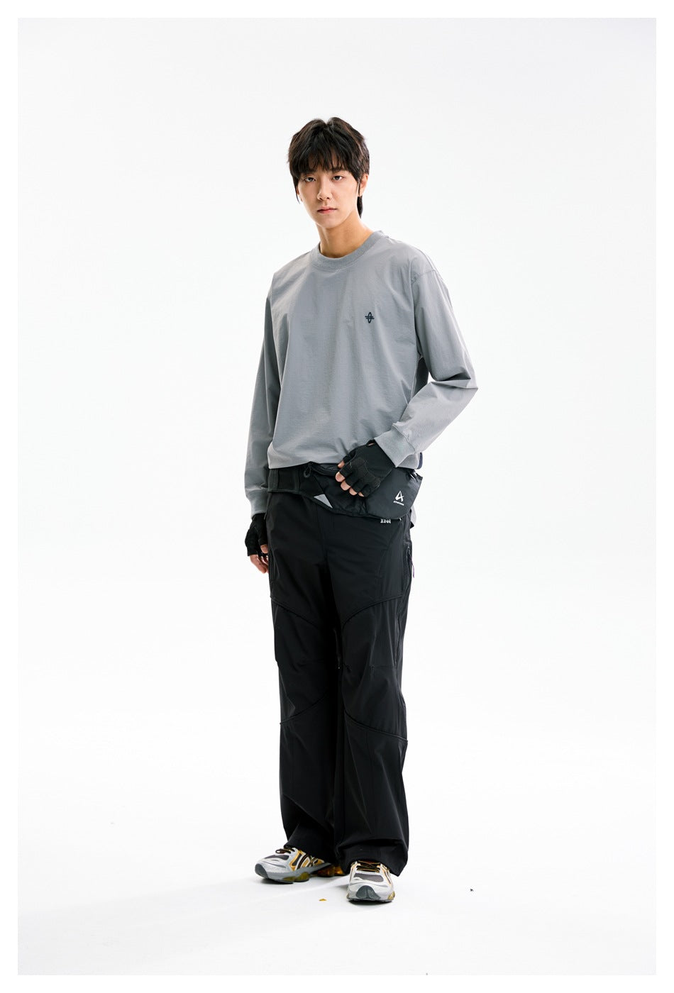 Model wearing the gray long-sleeve top with black wide pants, angled standing pose