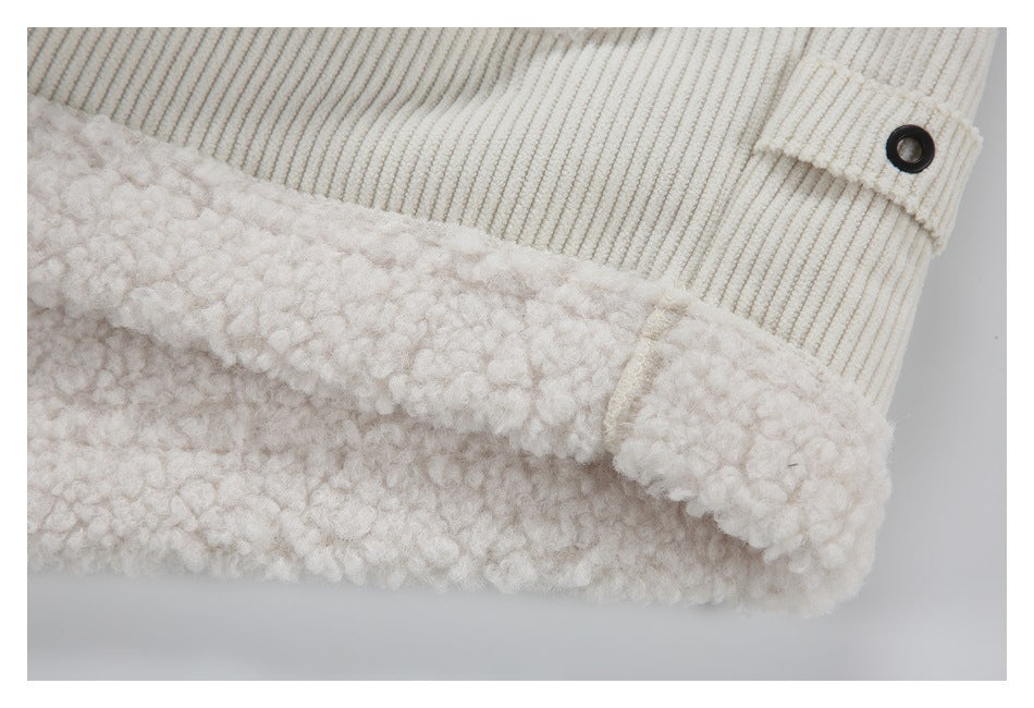 Close-up of a fuzzy ivory garment edge beside a ribbed tab with a black eyelet.