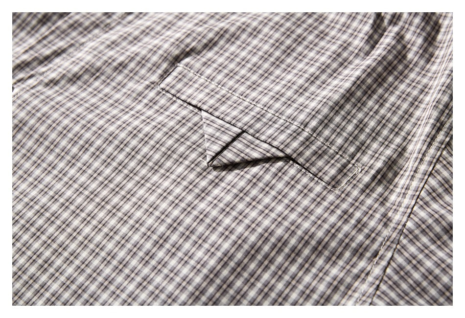 Close-up of a gray and cream checked shirt showing a single chest pocket and stitched edges.