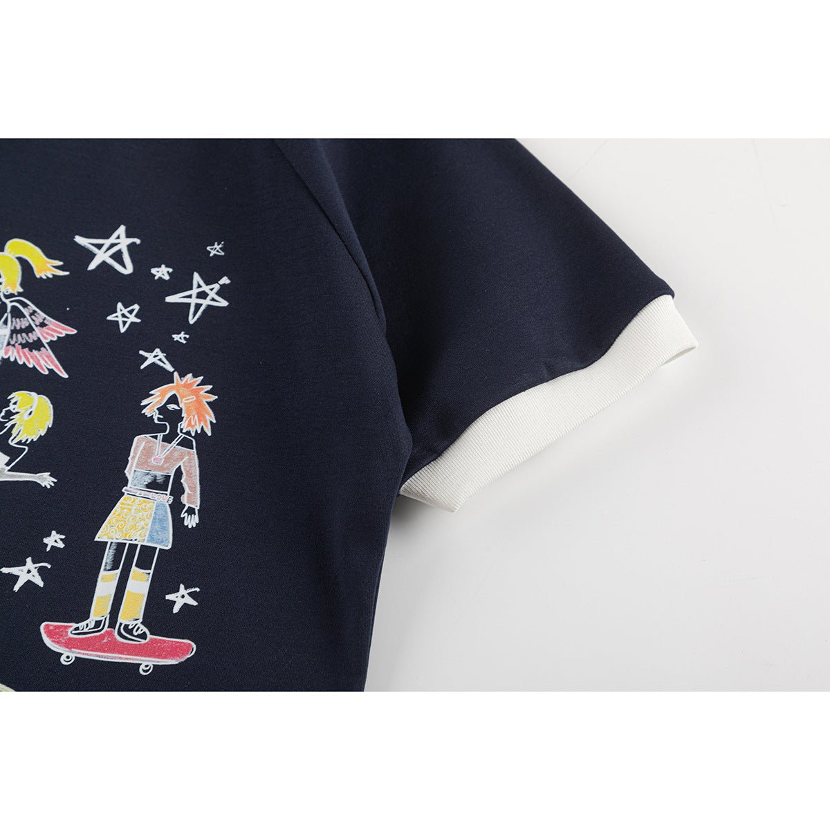 Close-up of the navy shirt's sleeve with a cream ribbed cuff and part of its colorful star-and-character print.