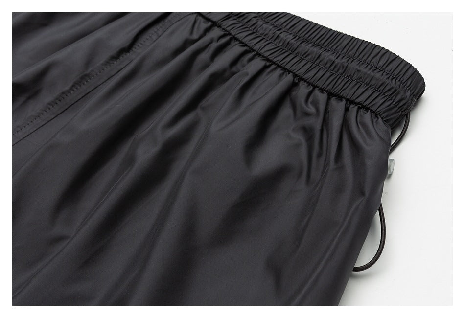 Close-up of black shorts with a gathered elastic waistband and side drawstring.