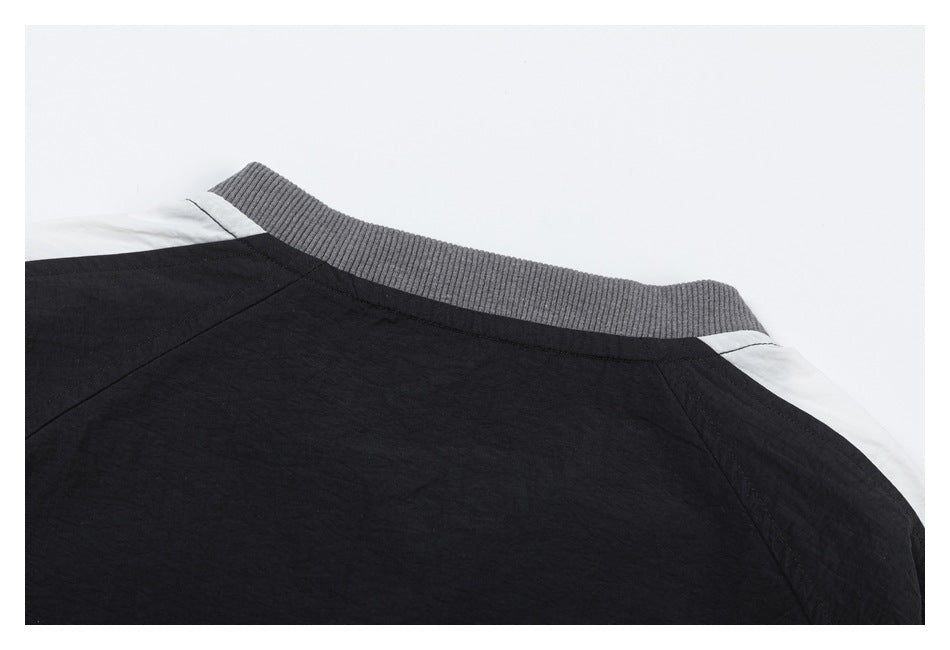Close-up of a black garment's upper back, with a gray ribbed collar and white shoulder panels.