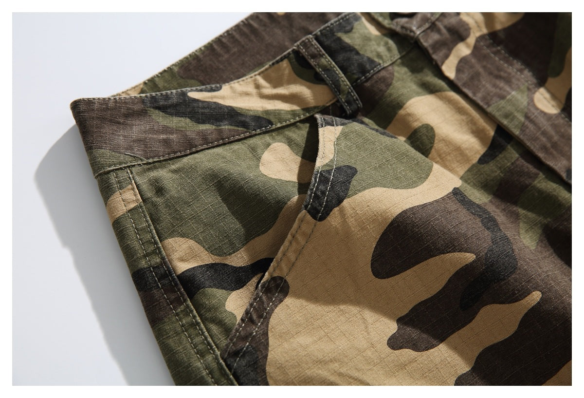 Close-up of a front pocket opening, waistband and stitching on camouflage pants.