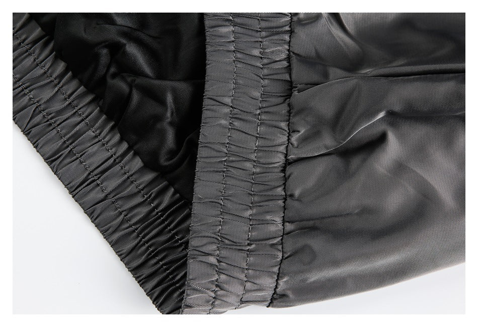 Close-up of gathered stitching and elasticized seam on dark gray garment fabric.