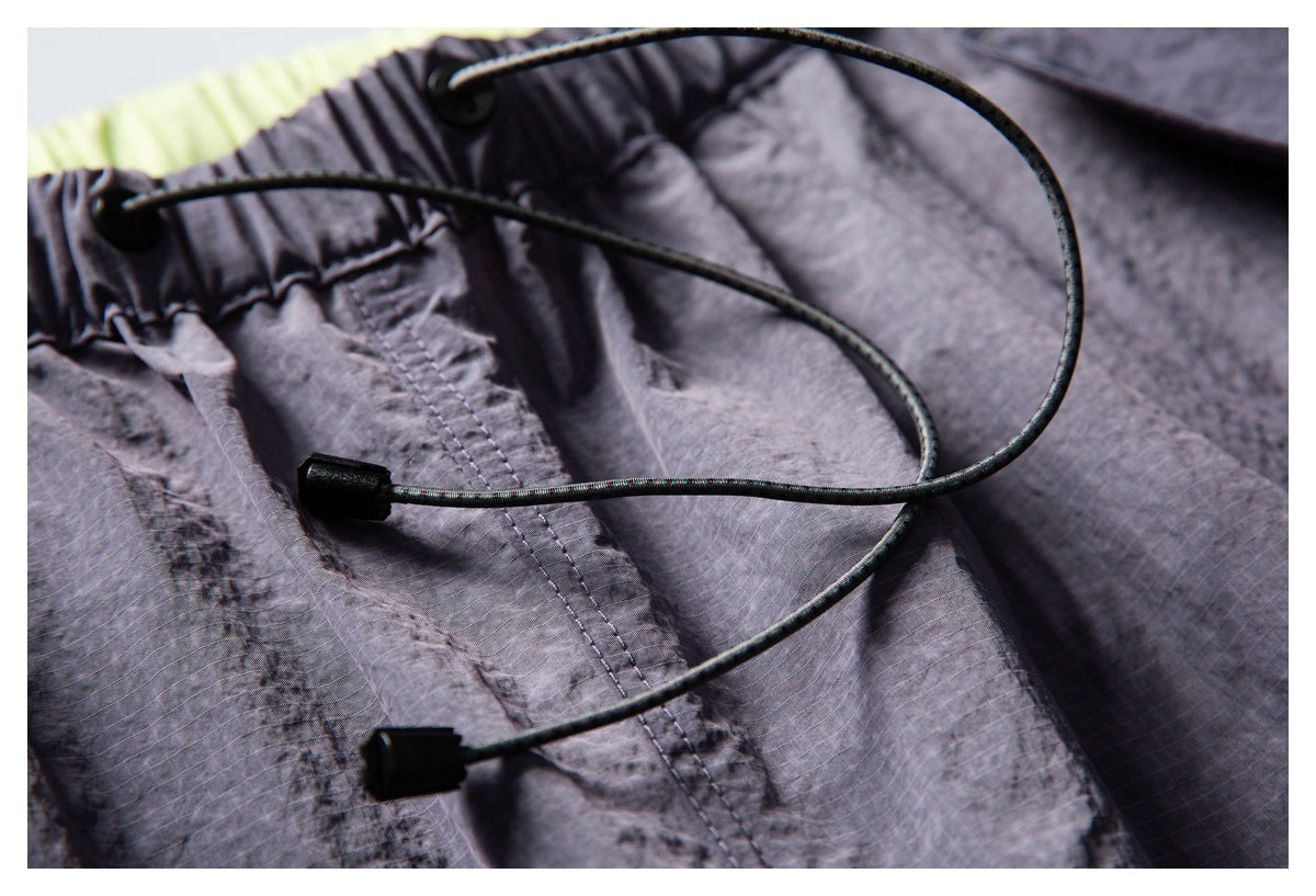 Close-up of the pants' elastic waistband and long adjustable drawcords with black cord ends.