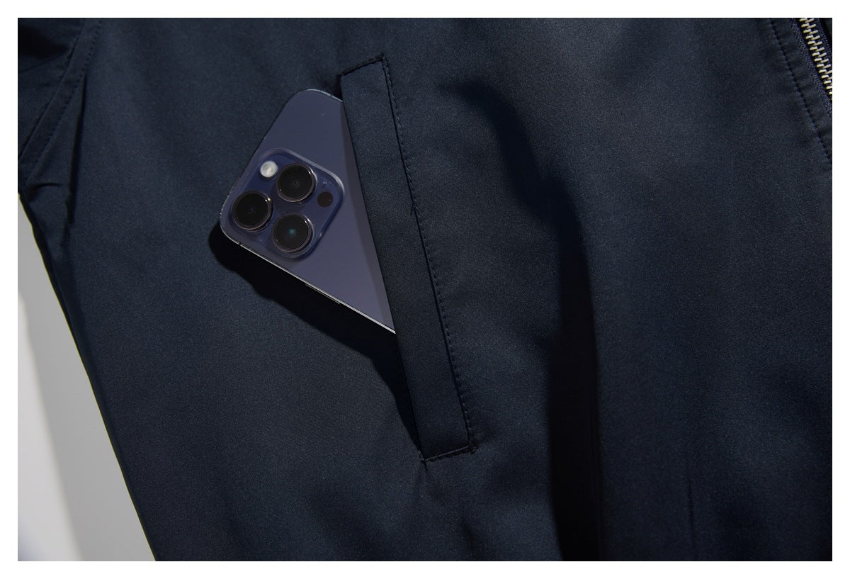 Close-up of a dark navy jacket pocket holding a smartphone, with a metal zipper visible at the edge.