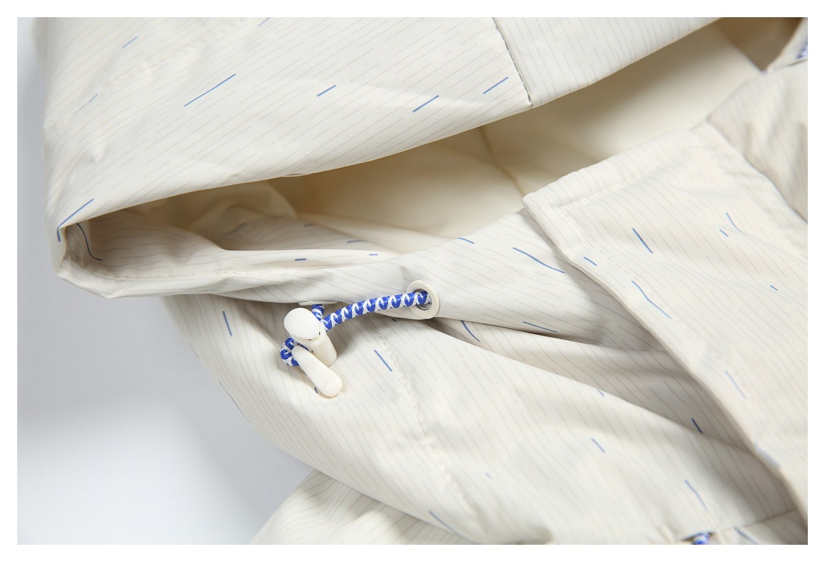 Close-up of a blue-and-white hood adjustment cord and toggle on the subtly patterned white jacket.
