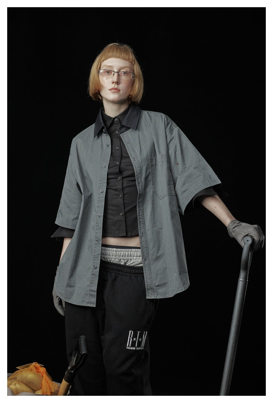 Closer view of a model wearing a gray short-sleeve button-up shirt over a black top, with a chest pocket and contrast collar.