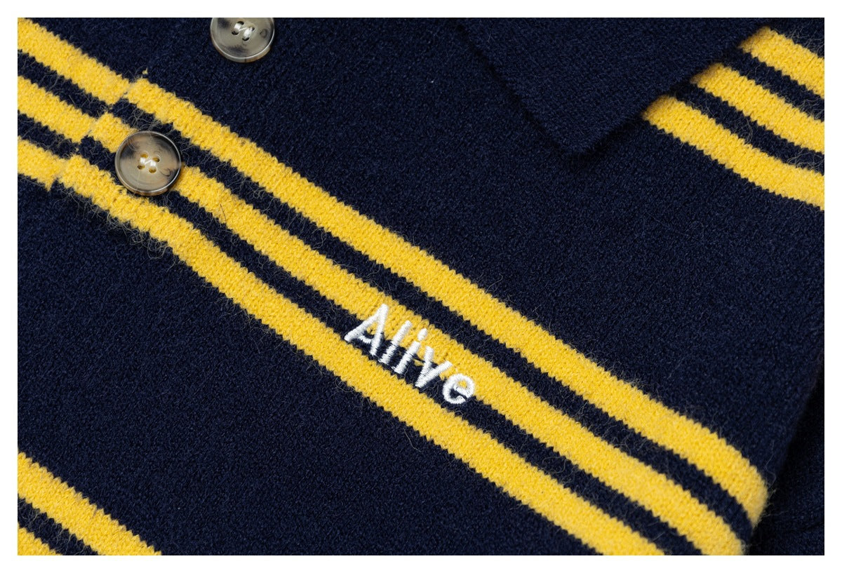 Close-up of navy knit fabric with mustard-yellow stripes, buttons, and small white embroidered lettering.