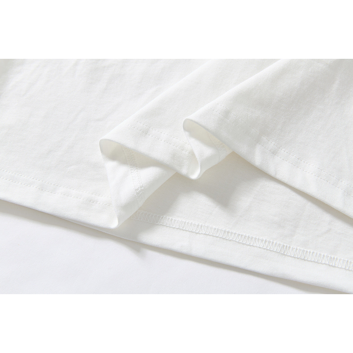Close-up of the white T-shirt's folded hem and visible seam stitching.